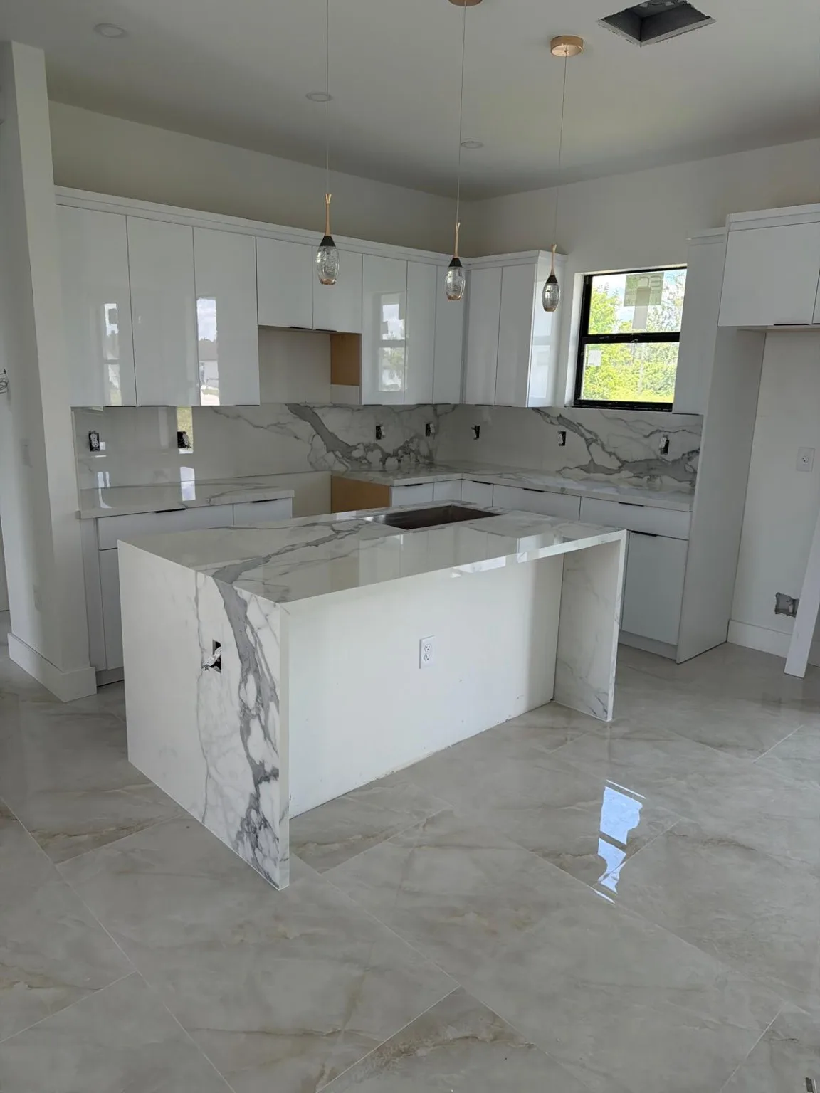 White kitchen cabinetry with stone countertops and waterfall island