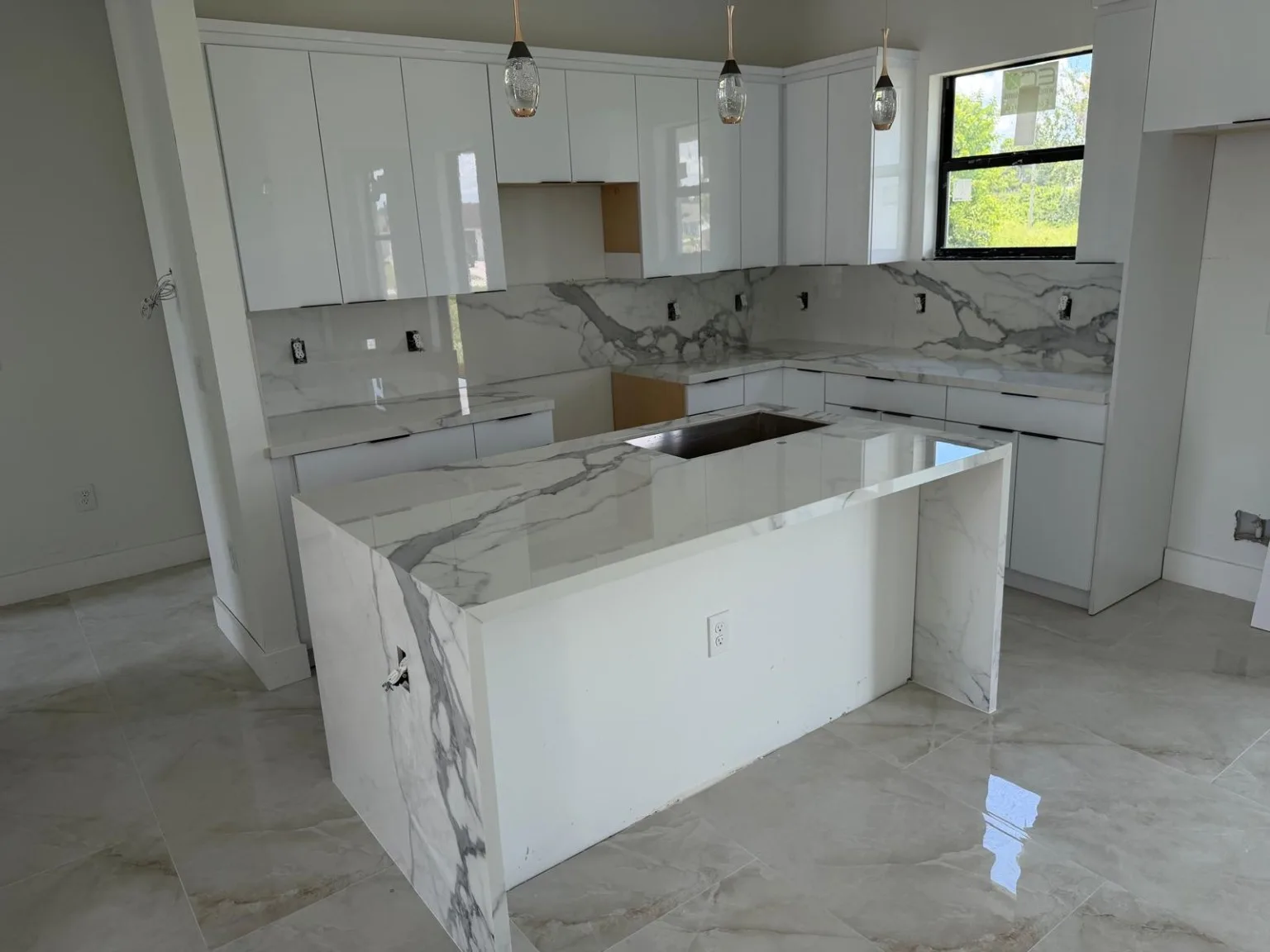 White kitchen cabinetry with waterfall countertop island