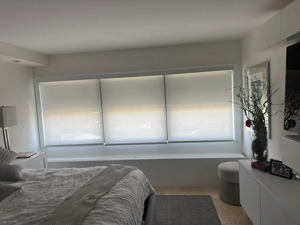 Roller shades installed on a row of bedroom windows