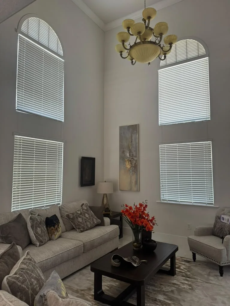 Faux-wood horizontal blinds fitted to tall arched two-story windows