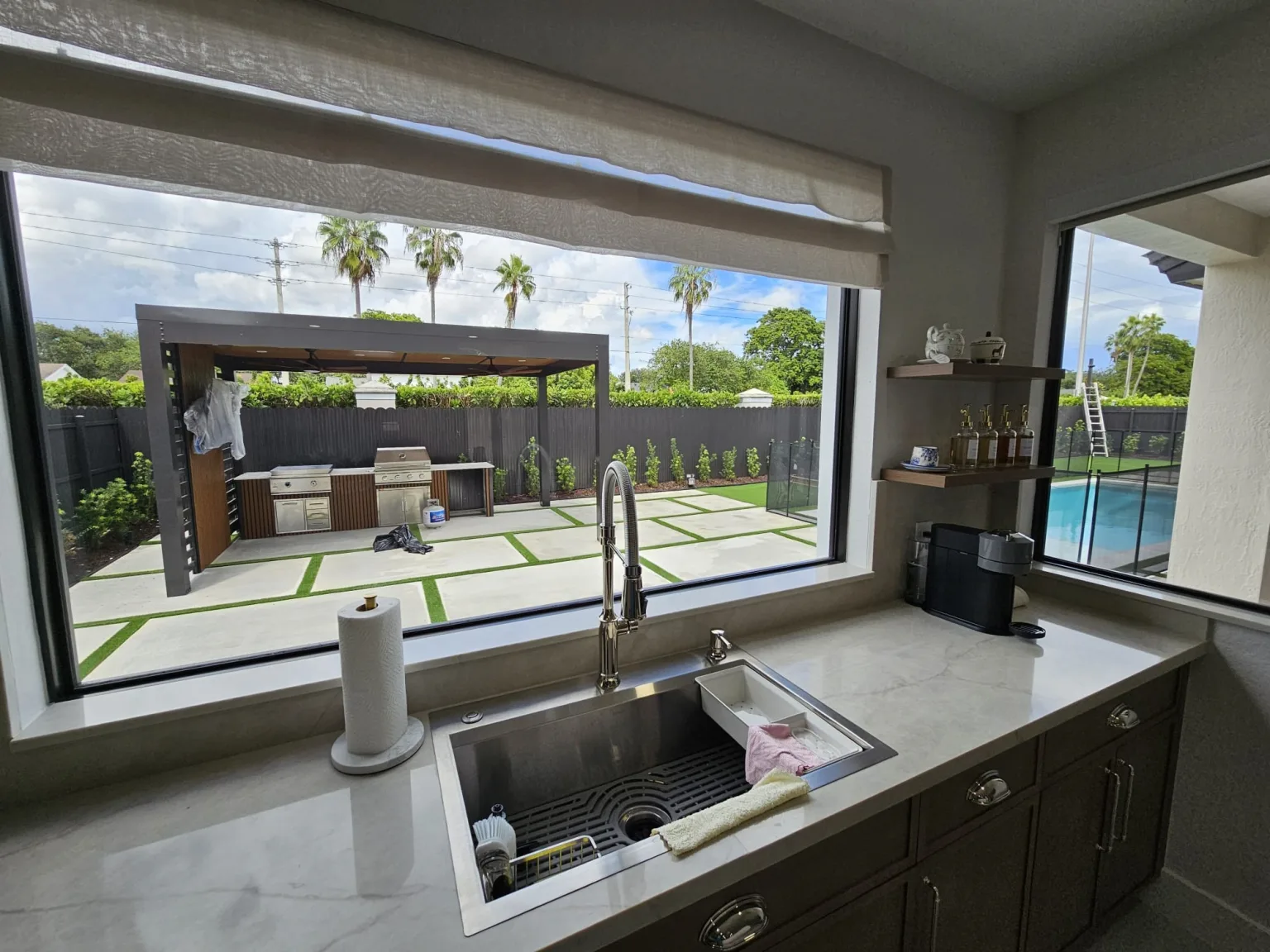 Kitchen window over the sink overlooking a covered patio with a pergola