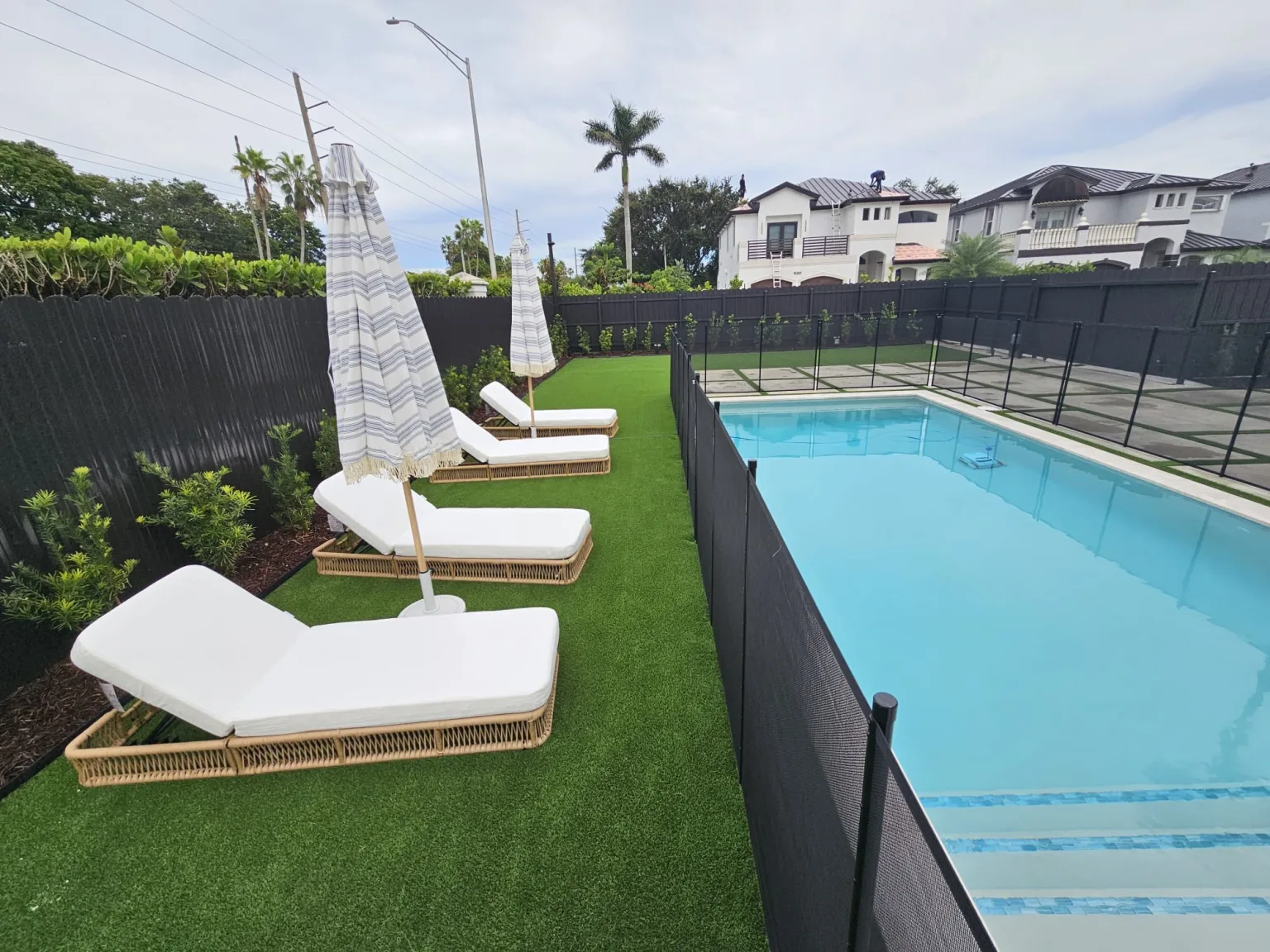 Completed outdoor environment with a pool, artificial turf and shaded lounge seating